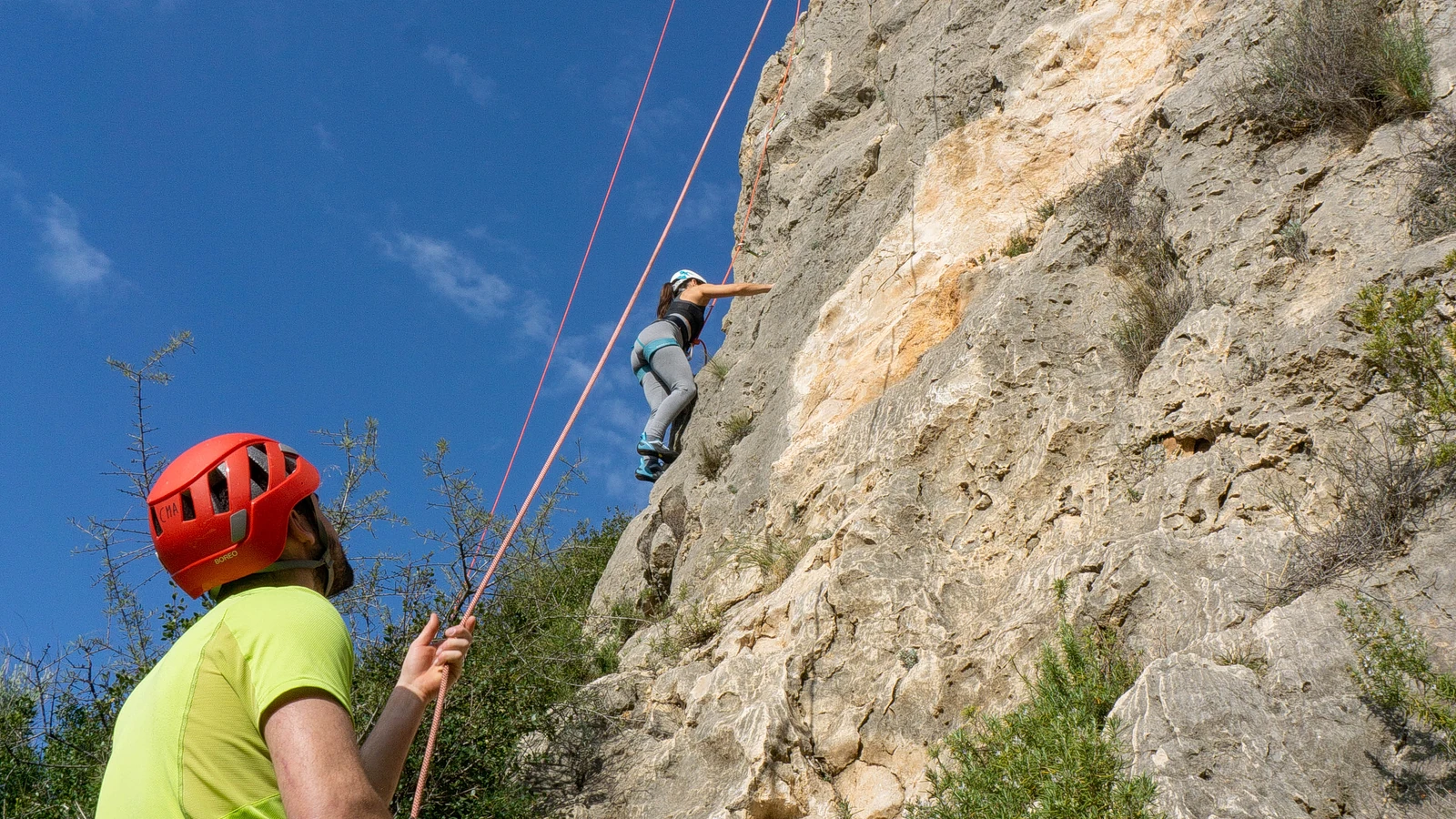 Participante y equipo durante un curso de escalada en roca